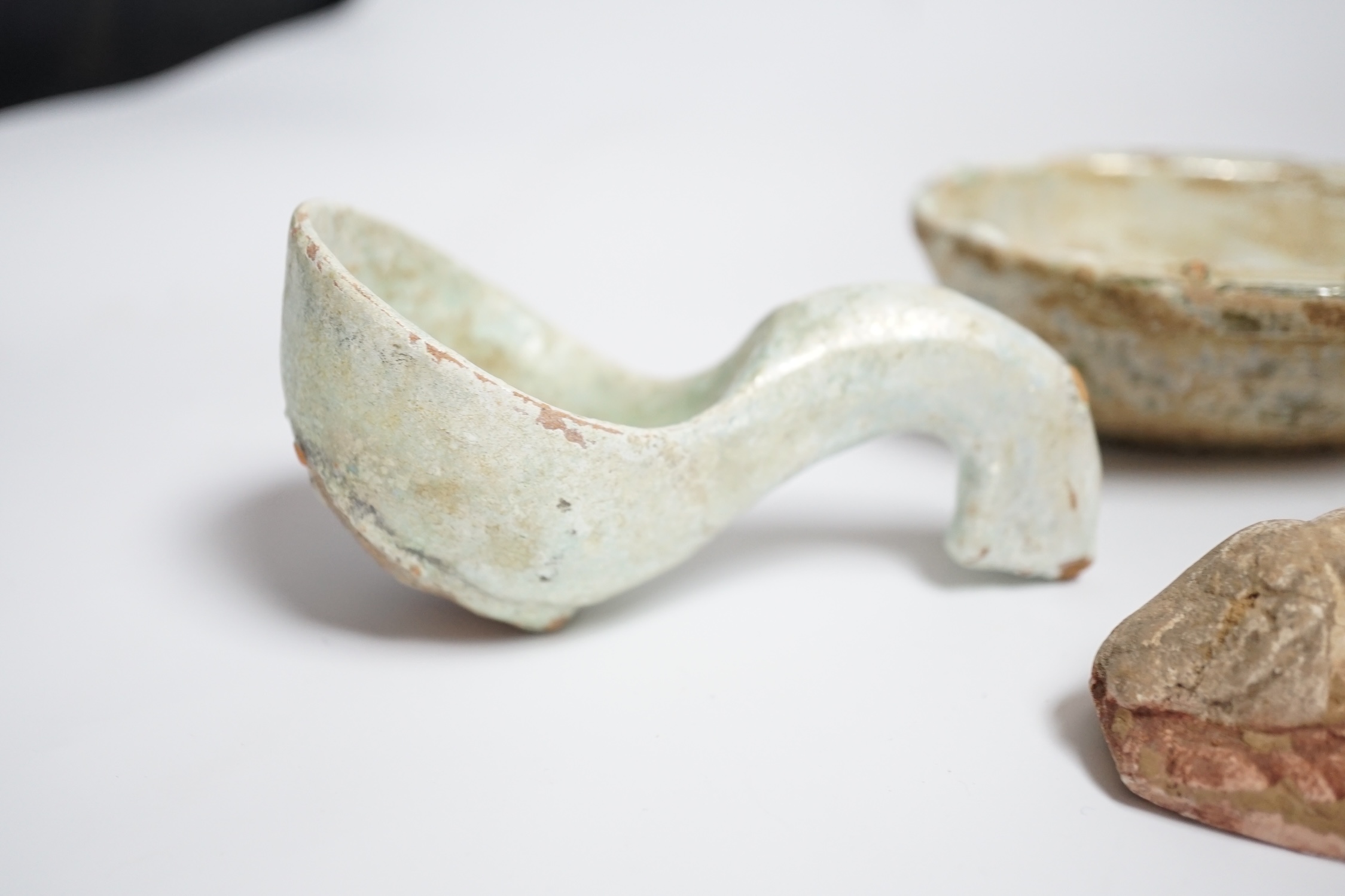 A Chinese glazed pottery ‘ear’ cup and similar spoon, Han dynasty, and a pottery figure, Song dynasty, largest 13cm wide